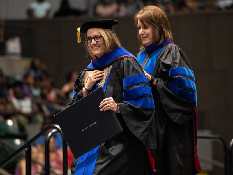 After receiving her Ph.D. in Nursing, Katie Hall, left, is hooded by Dr. Jennifer Robinson, one of her professors.