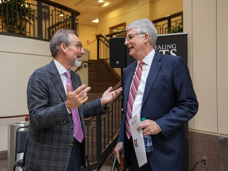 Malcolm White, left, executive director of the Mississippi Arts Commission, offers an impassioned critique of the proceedings to Tom Fortner, father of Frances Anne and UMMC's chief institutional advancement officer.