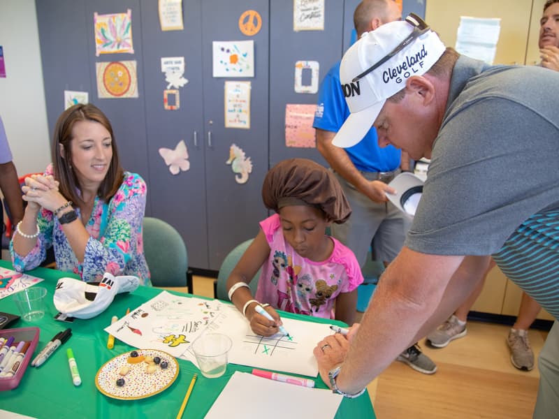 Cheri Potter and husband, Sanderson Farms Championship golfer Ted Potter Jr., play tic-tac-toe with Children's of Mississippi patient Mylaijah Simmons of Laurel.