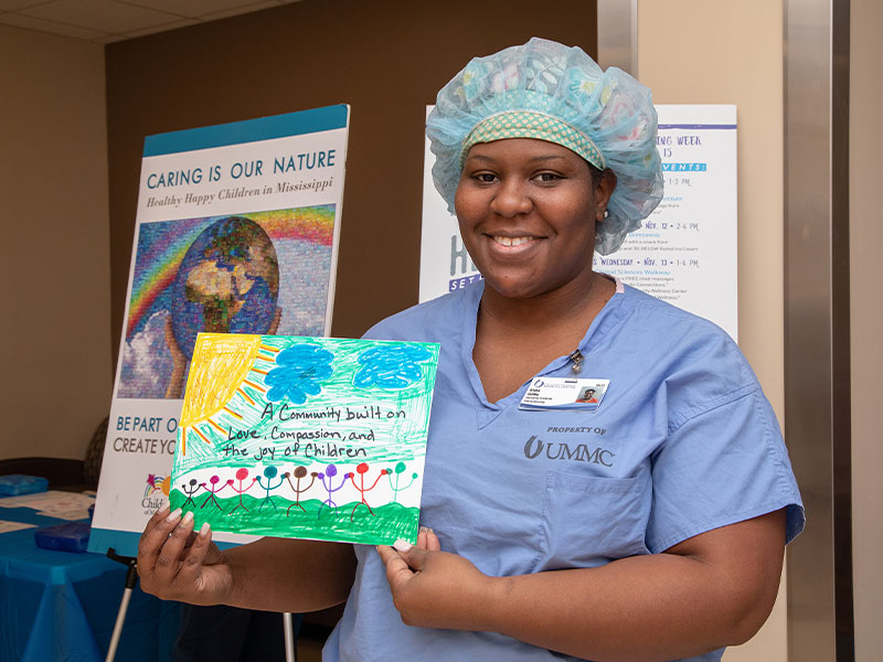 Anesthesia tech Ericka Griffin shows her contribution to the mural that will we a focal point of the children's hospital expansion's lobby.