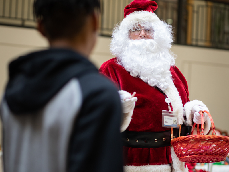 Santa Claus hands out candy canes to passers by inside the adult hospital atrium.