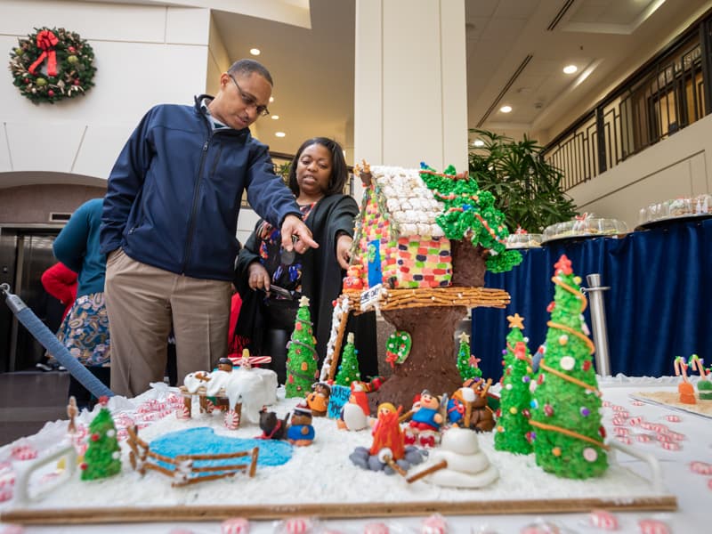 Donor heart recipient Timothy Lewis, left, and Patrice Donald, magnet program manager in the Office of Nursing Quality and Development, check out Nursing Quality's entry into UMMC's annual gingerbread house competition. Nursing Quality's entry took second place.