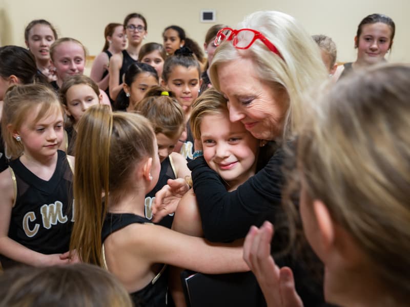 Surrounded by fellow dancers, Sybil gets a hug from her dance teacher, Carol Merrill.