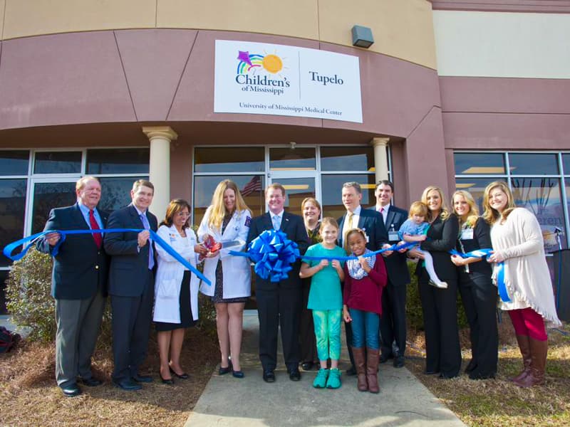 A group of people cuts the ribbon in front of the Children's of Mississippi Tupelo Clinic.