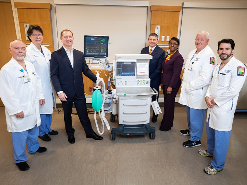 Group of people posing with anesthesia machine.