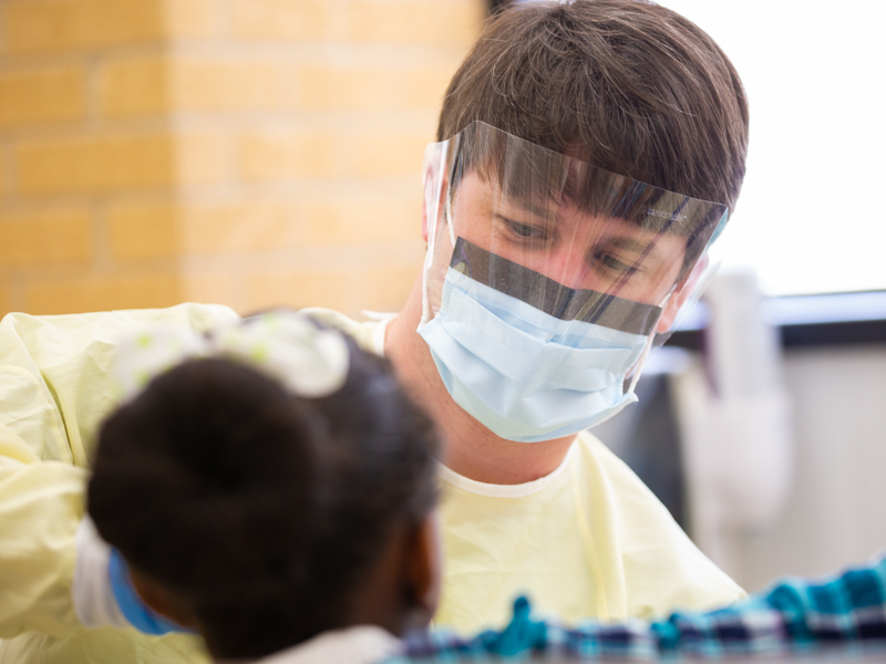 Close up of dental student working with patient in foreground.