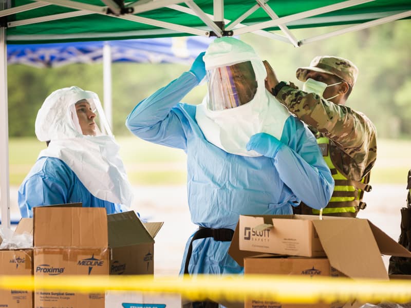 UMMC employees and students put on personal protective equipment fo COVID-19 sample collections April 8 at Traceway Park in Clinton.