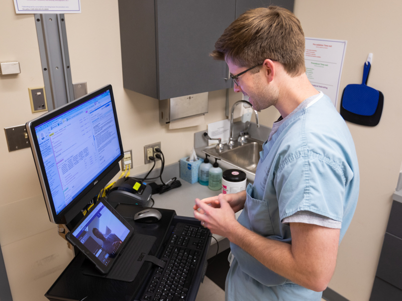 Dermatology Resident Dr. Mark Braswell sets up his telehealth equipment in preparatoin for patient videoconferencing.