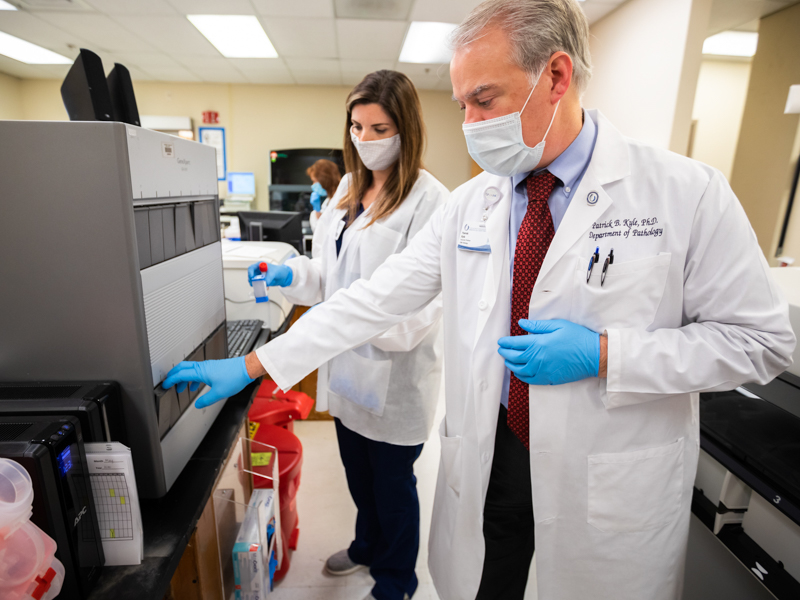 Dr. Patrick Kyle, a toxicologist and associate professor of pathology, and medical laboratory technician Ashleyanne Westbrook perform testing on COVID-19 specimens.
