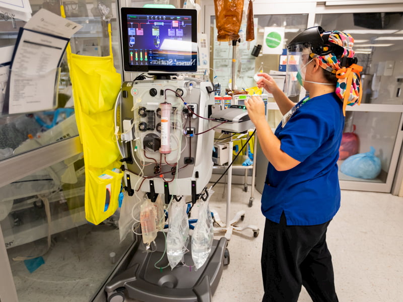 Registered nurse Melissa Collins makes adjustments to a continuous dialysis machine that supports the kidneys of a COVID patient in the medical ICU. UMMC is one of a few hospitals in the state, if not the only, with that technology.
