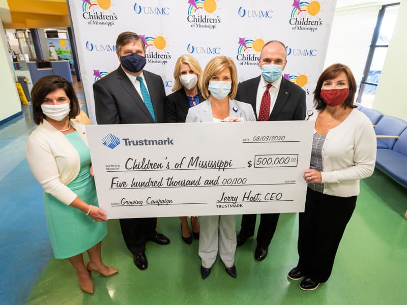 Smiling behind their masks about Trustmark's philanthropy and support of children's health care are, from left, Melanie Morgan, Trustmark senior vice president and director of corporate communications and marketing; Jerry Host, Trustmark chairman and CEO; Meredith Aldridge, Children's of Mississippi director of development; Dr. LouAnn Woodward, UMMC vice chancellor for health affairs; Duane Dewey, Trustmark president and COO; and Dr. Mary Taylor, Suzan B. Thames Chair and professor and chair of pediatrics.