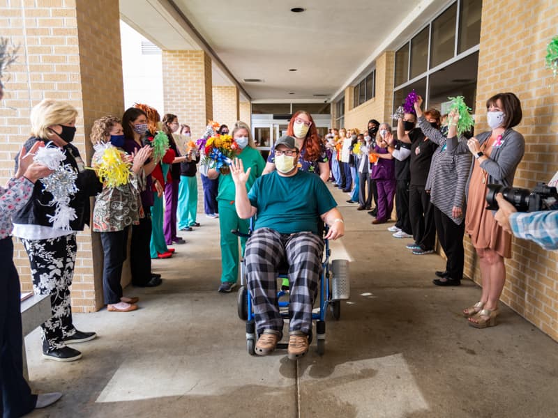 Front-line caregivers at the Medical Center cheer on Raleigh resident Timothy Hudson, the 1,000th patient with COVID treated at UMMC, as he departs following a one-week stay.