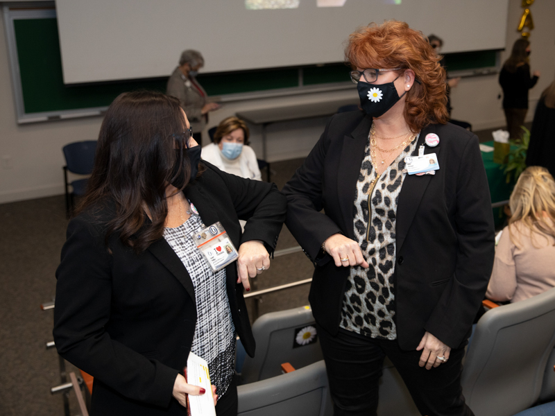 Kaye Flanagin, nurse manager for the nursing service office and the nurse resource team at the University of Mississippi Medical Center, receives a congratulatory elbow bump from Jacque Phillips, manager of nursing standards in Nursing Quality and Development.