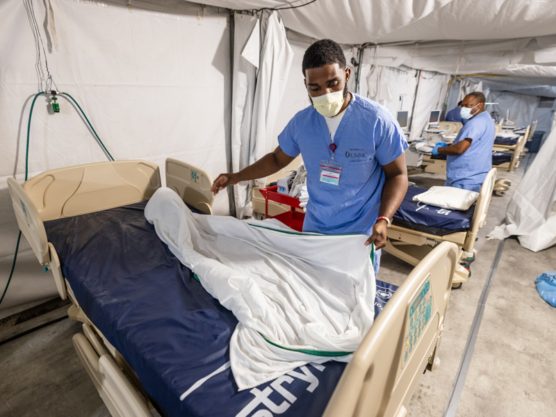 Ronald Turner puts sheets on a hospital bed Friday before the opening of the COVID-19 field hospital at UMMC.