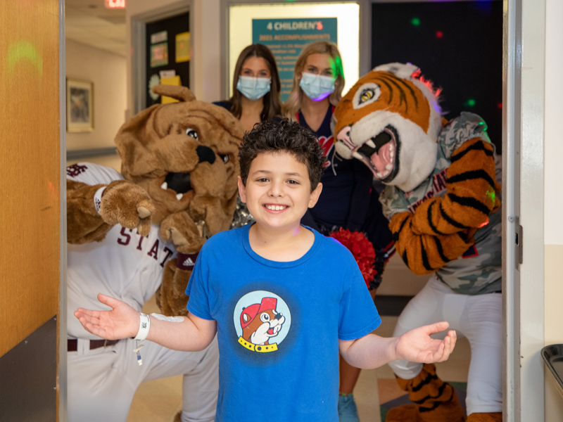 Children's of Mississippi patient Jaxson Coleman of Clinton got a surprise visit from, from left, Mississippi State mascot Bully, Ole Miss dance team member Jane Granberry and cheerleader Mara Liston, and Jackson State mascot Sonny Thee Tiger. Jay Ferchaud/ UMMC Communications