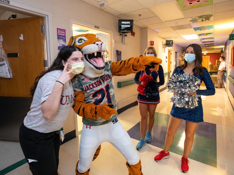 Children's of Mississippi nurse Jenny Lowery smiles with Sonny Thee Tiger of Jackson State as cheerleader Mara Liston, left, and dance team member Jane Granberry of Ole Miss look on.