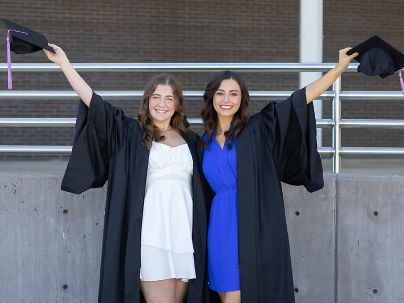 Dental Hygiene graduates Kate McCarthy and Cassie Ingram pose for celebratory photos after commencement.