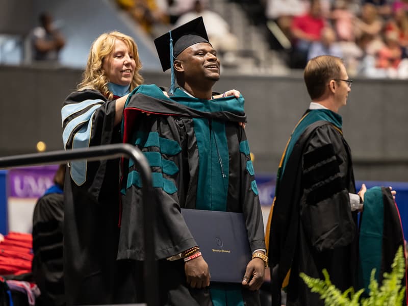 Dr. Kimberly Willis, associate professor with the School of Health Related Professions, hoods Doctor of Physical Therapy graduate Kendrique Morgan.
