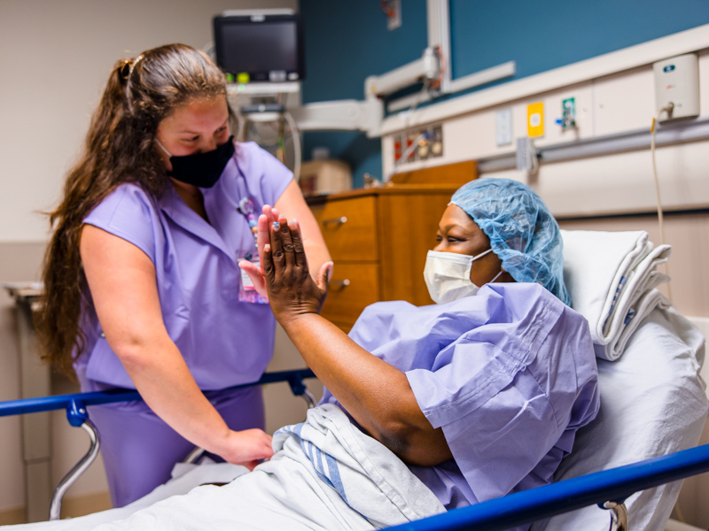 Registered nurse Madison Burge gives Tawanna Davis a comforting high-five before Davis is wheeled to the OR for kidney transplant surgery. Lindsay McMurtray/ UMMC Communications