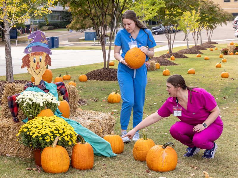 Anna Minga and Emery Applegate, students in the School of Health Related Professions, choose pumpkins at the UMMC pumpkin patch. Jay Ferchaud/ UMMC Communications 