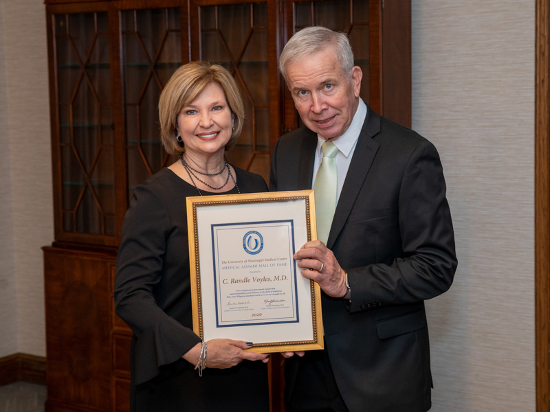 Voyles receives a Medical Alumni Hall of Fame certificate from Dr. LouAnn Woodward ('91), vice chancellor for health affairs and dead of the School of Medicine, in November.