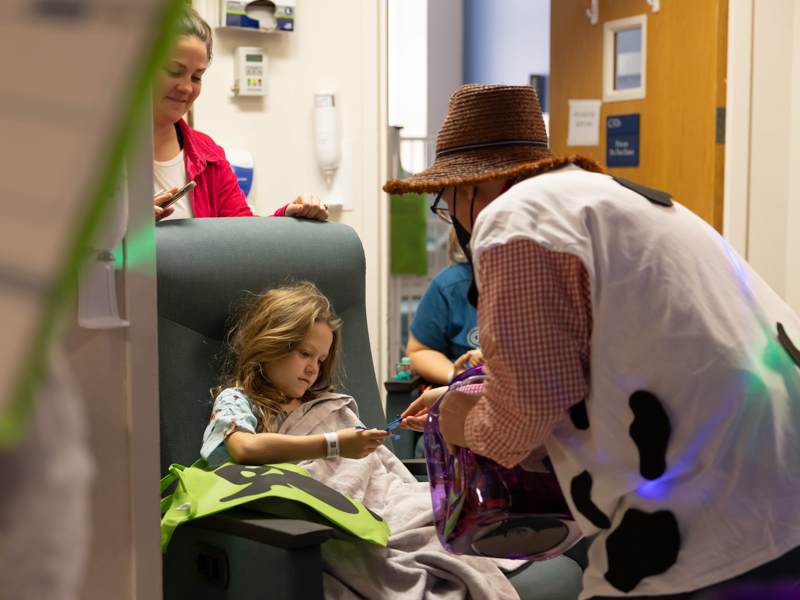 Children's of Mississippi patient Presley Beassie of Wesson gets a Halloween treat from Patrick Cooper as her mom, Kelsey Beassie, looks on. Melanie Thortis/ UMMC Communications