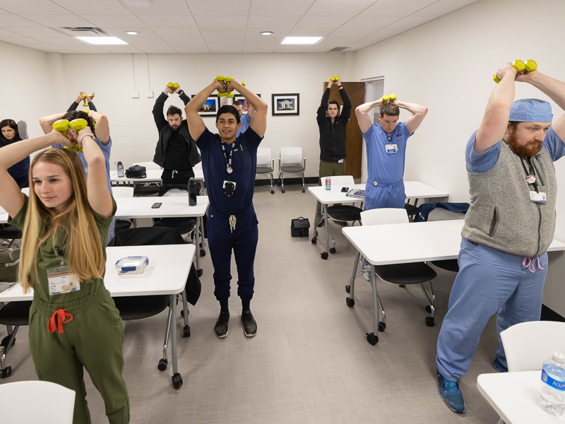 Radiology residents Dr. Abdullah Shaheen, from left, Dr. Matin Goldooz, Dr. Lydia Rose, Dr. Will Crews, Dr. Tito Martinez, Dr. Kirby Parker, Dr. James Decker and Dr. Thomas Young lift weights to tone their arms as part of a Department of Radiology wellness exercise.