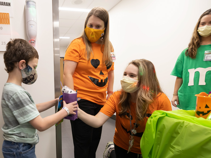 Children's of Mississippi patient Gabriel Varner gets Halloween treats from child life specialists, from left, Courtney Easterday and Madeline Wilson as School of Pharmacy student Emily Nichols looks on. Melanie Thortis/ UMMC Communications 