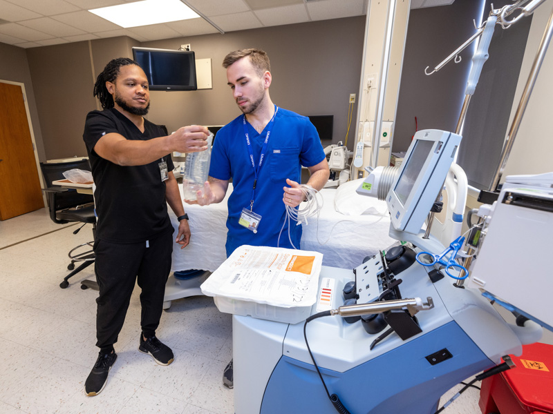 Registered nurse supervisor Shelby McNair, left, and registered nurse Caleb Pace prepare equipment they will use to remove stem cells from the blood of a BMT donor in the unit's apheresis laboratory. Jay Ferchaud/ UMMC Communications 