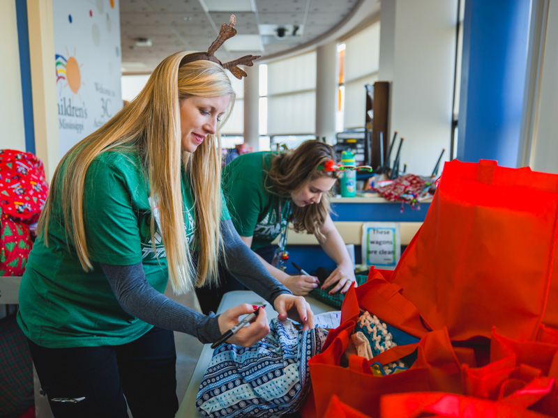 Anne Elizabeth Zegel and Madeline Wilson, child life specialists, help Santa prepare bags for holiday deliveries during his annual visit to Children's of Mississippi. Lindsay McMurtray/ UMMC Communications 