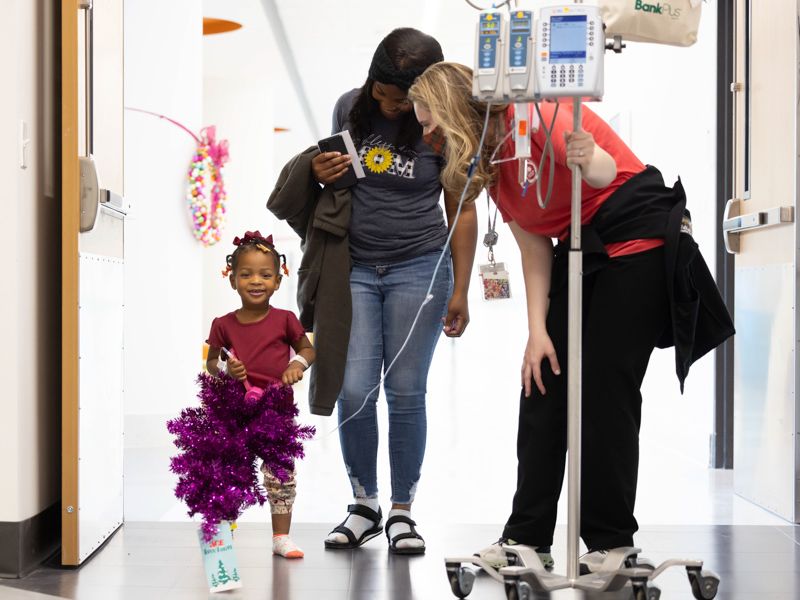 Two-year-old Logan Nash carries her Christmas tree down the halls of Sanderson tower with her mother, Derrion McCoy and child life specialist Madeline Wilson following their BankPlus Presents Winter Wonderland visit at Children's of Mississippi. Melanie Thortis/ UMMC Communications 