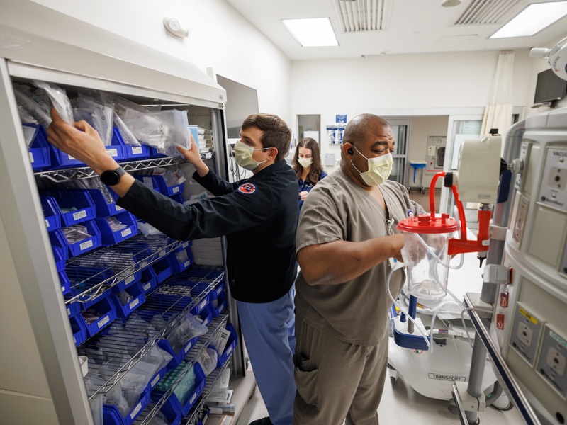 Dr. Andrew Garza, left, Pharmacist Stephanie Tesseneer, background, and Respiratory Therapist Charles Patton stock supplies in a Trauma Room in the Adult Emergency Department at the University of Mississippi Medical Center.