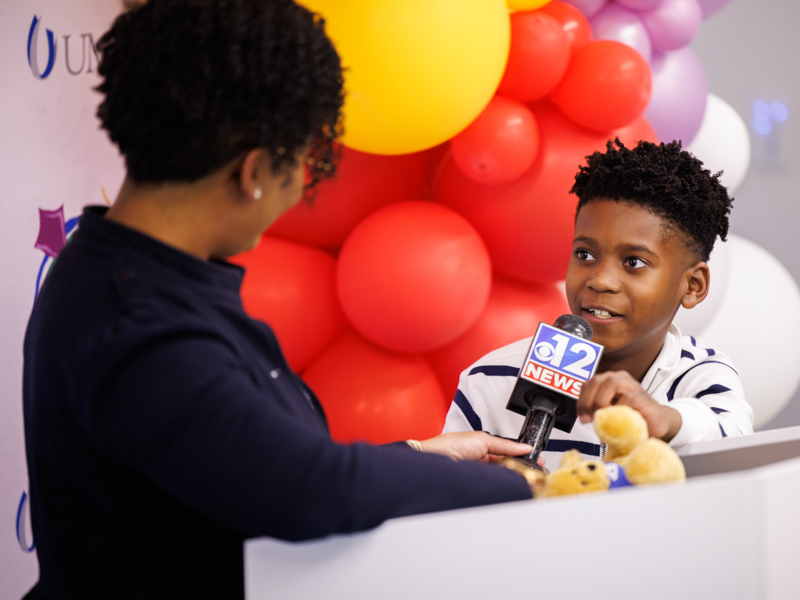 Kingston Murriel and mom Liz Foster exchange glances during a news conference announcing him as the state's 2023 Children's Miracle Network Hospitals Champion.