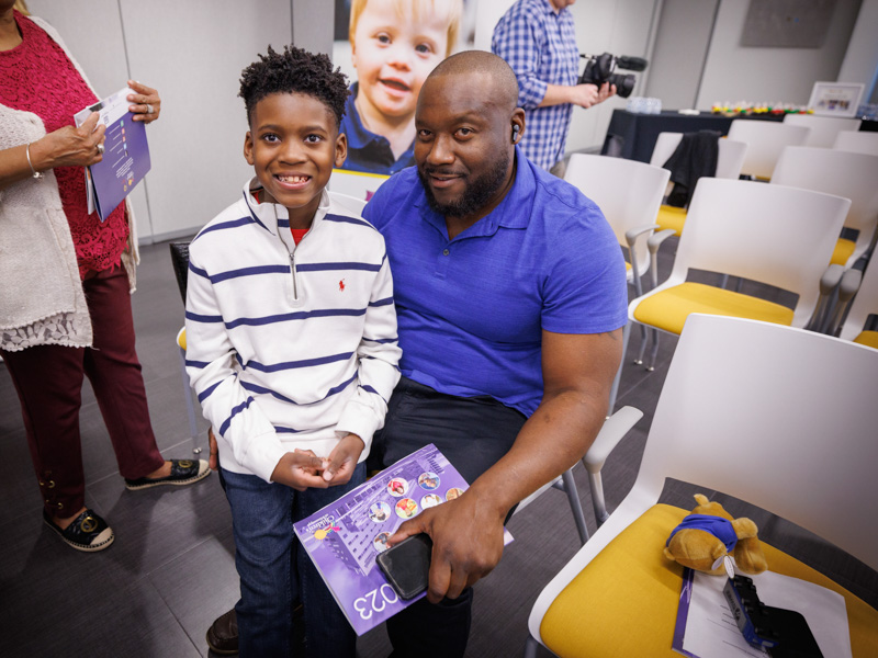 The Murriel men, Kingston and dad Marcus, smile after Kingston's announcement as the 2023 Children's Miracle Network Hospitals Champion for Mississippi.