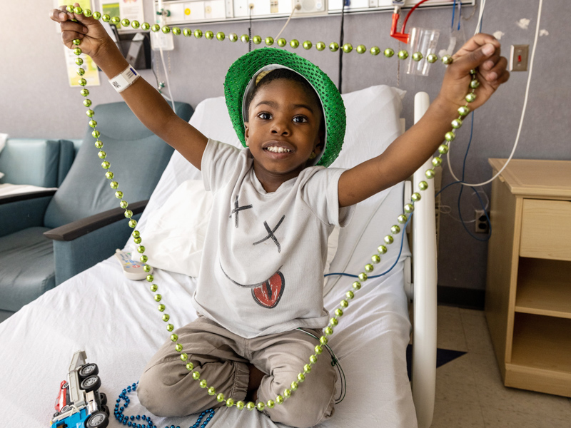 Children's of Mississippi patient Aiden Williams of Jackson plays with Mardi Gras beads after a Friends of Children's Hospital indoor parade Tuesday afternoon. Jay Ferchaud/ UMMC Communications 