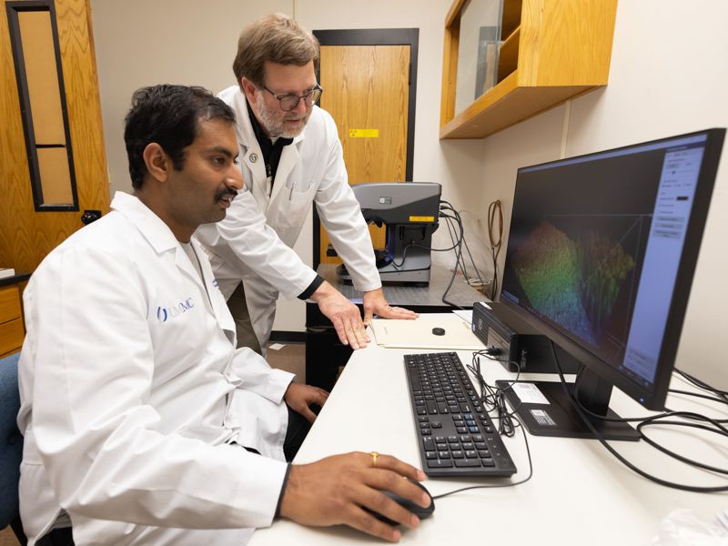 Dr.Jason Griggs, right, and Dr. Kartikeya Jodha, a postdoctoral fellow, study a specimen using a Keyence America 3D surface profiler laser microscope.