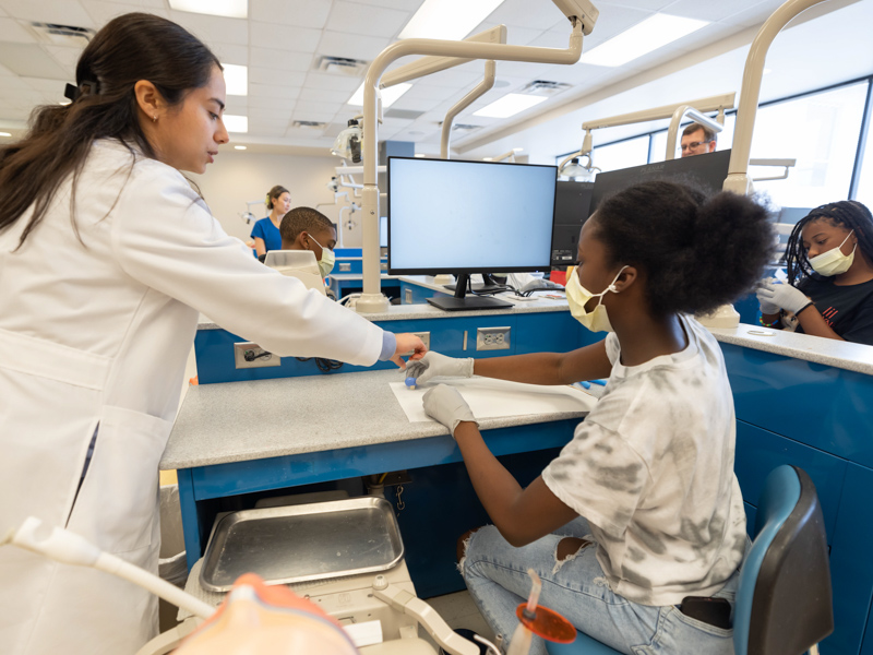 Twelve-year-old Hanna Winfrey shapes a dental mold with the help of School of Graduate Studies in the Health Sciences student Jaccare Jauregui Ulloa as part of S.M.I.L.E U at the School of Dentistry.