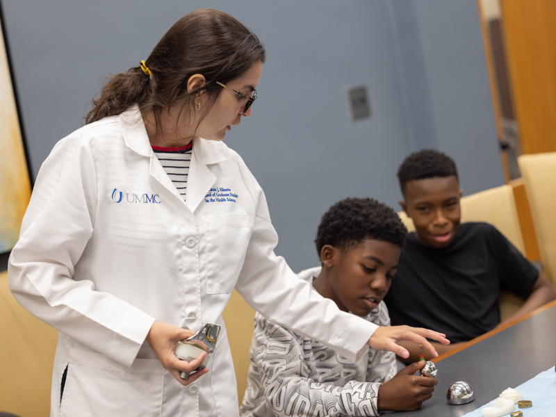 School of Graduate Studies in the Health Sciences PhD student Laura Alberto talks with Josiah Mangum, 12, about metal bone implants during S.M.I.L.E U at the School of Dentistry.
