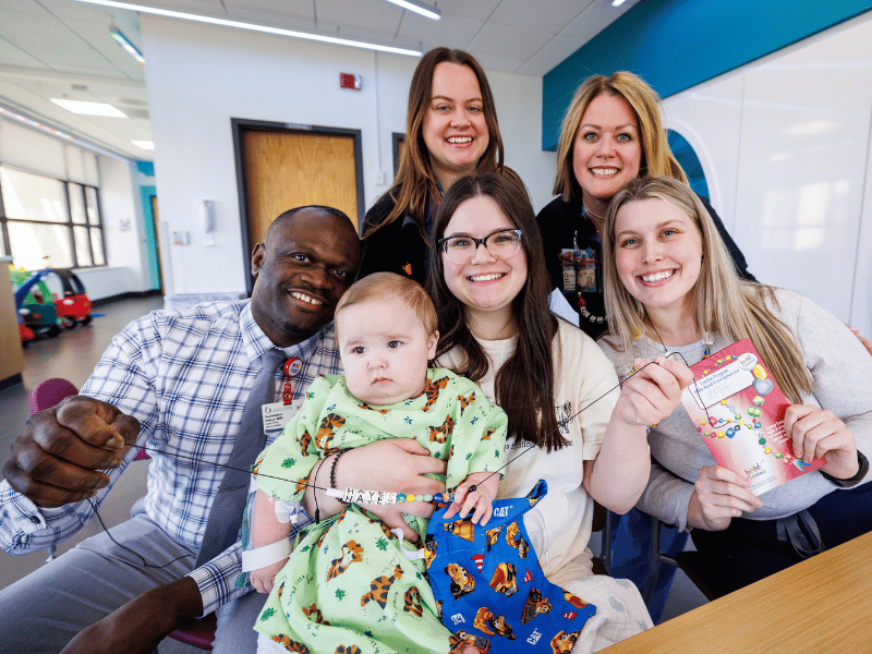 Smiling with Hayes Clayton, the first Children's Heart Center patient at Children's of Mississippi to receive Beads of Courage, are, from left, pediatric cardiologist Dr. Onyekachukwu Osakwe, nurse educator Jessica Brister, Children's Heart Services director Alicon Johnson and child life specialist Allyson Holliman. Holding Hayes is mom Riley Strickland.