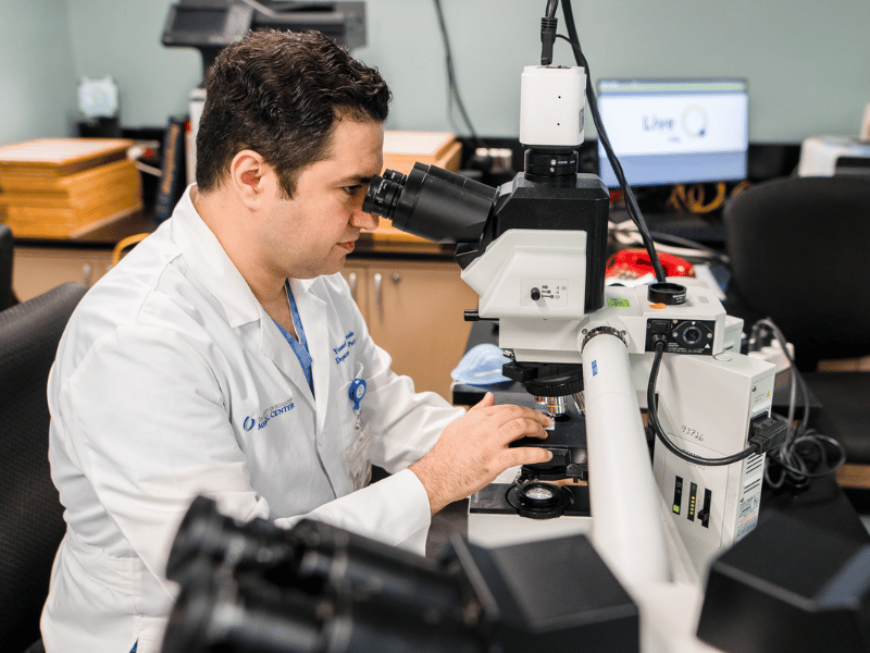Dr. Youssef Al Hmada, associate professor and director of anatomic pathology, examines slides in the lab. LM 