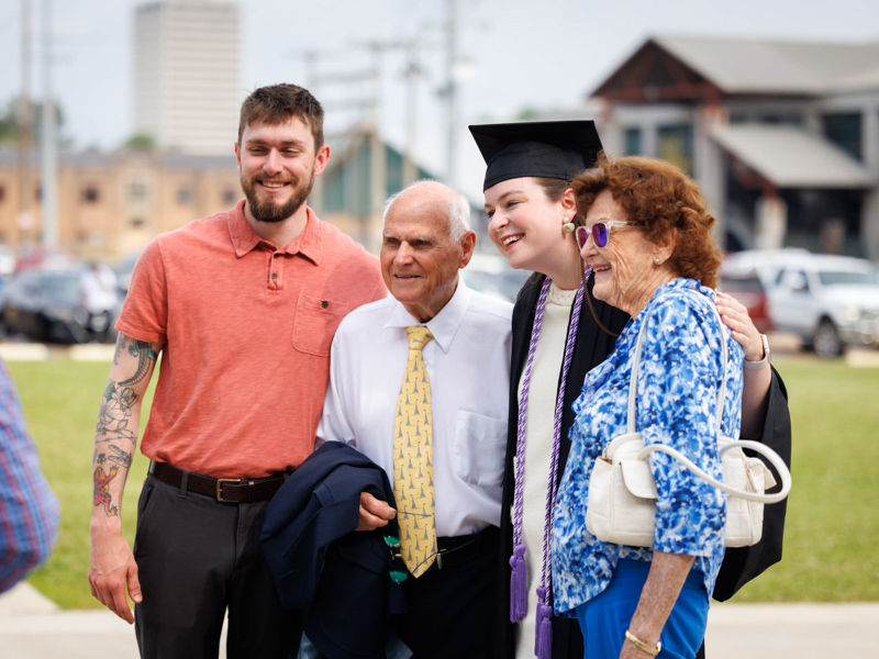 Capped and enrobed, Bachelor of Science in Nursing graduate Olivia DeGrado takes a photo with brother, Michael DeGrado, and her grandparents, Joe and Ruth DeGrado. Joe Ellis/ UMMC Communications 