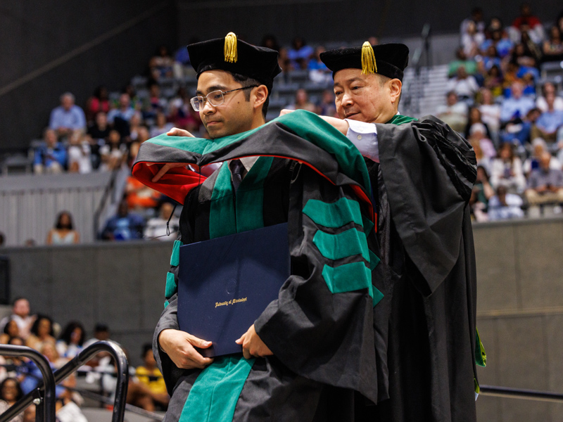 Graduate Ernest Lam is hooded by his father, Dr. John Lam, professor of Pathology. Jay Ferchaud/ UMMC Communications 