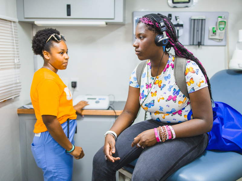 Volunteer Karsyn Hampton gives Amariannah Cheve a hearing test in the School of Nursing's mobile clinic.