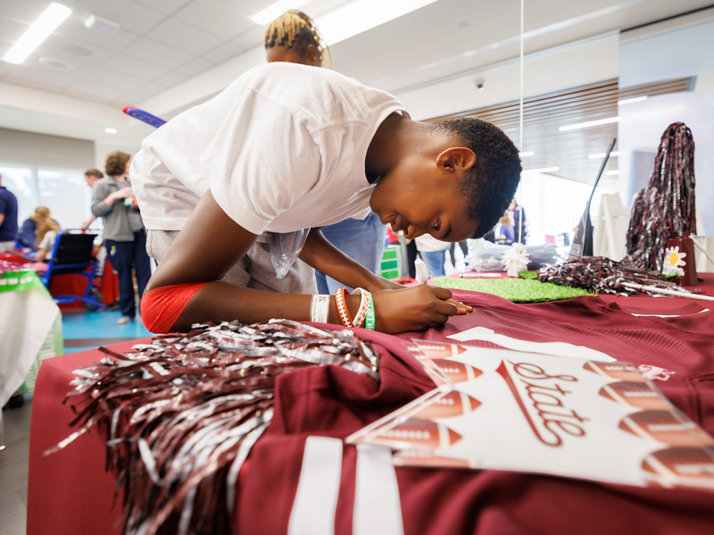 Children's of Mississippi patient Kendall Cooley of Moss Point signs a Mississippi State jersey during a Friends of Children's Hospital Tailgate Party.