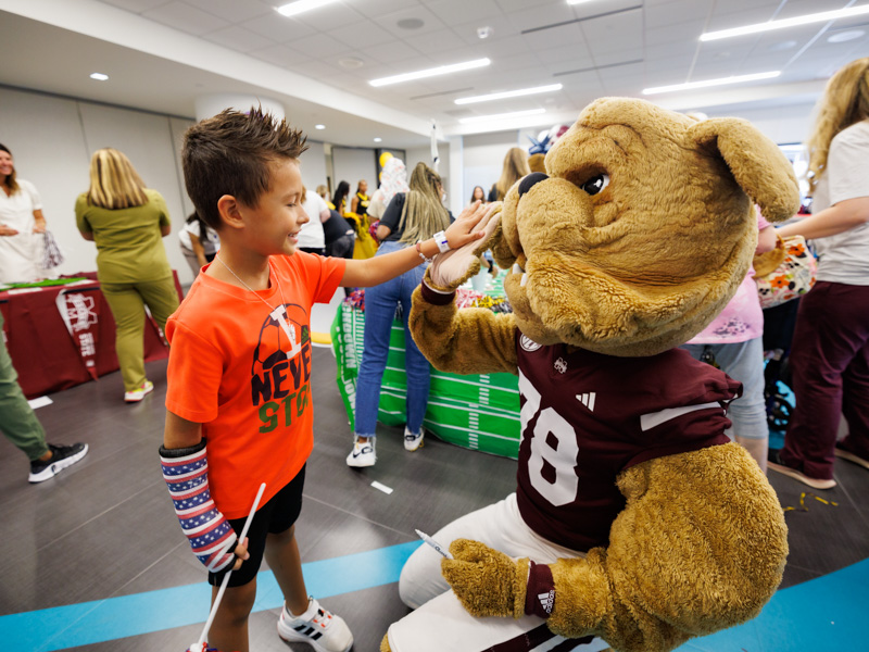 Logan Manjarrez, 7, of Koscuisko gives Mississippi State University mascot, Bully, a high-five during a Friends of Children's Hospital Tailgate Party.