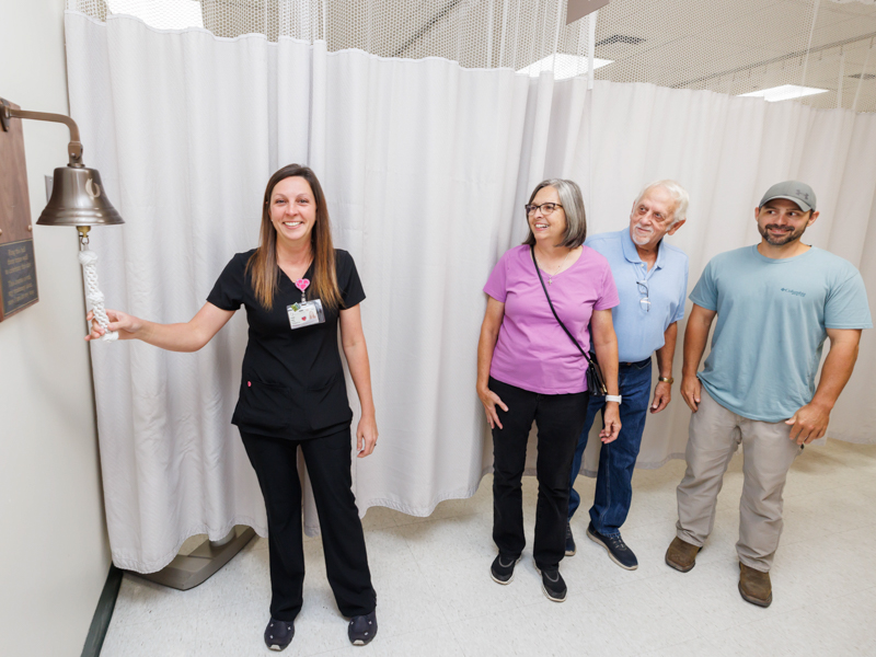 Registered Nurse Jessica Greer rings the bell as parents, Lori and Charles Blakely, and her husband, Chris Greer, look on at the UMMC Grenada Cancer Center and Research Institute.