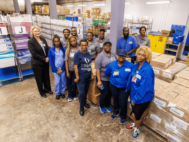 Rachel Harkness, supply chain director, stands by members of the Storeroom Management and Replenishment Teams including, back row, from left, Keonna Mims, Clifton "CJ" Walker, Avery Rhodes, Chante Bradley, Sekina Lewis, Calvin Alexander, Alecha Gibbs; front row, from left, Tawanna Bell, Linda Bennett, Vicky Bulley, Ebony Fults and Angela Crockett.