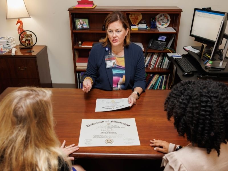 Office of Enrollment Management Executive Director Dr. Emily Cole talks with Brittney Anthony and Lauren Nichols about diploma layout changes.