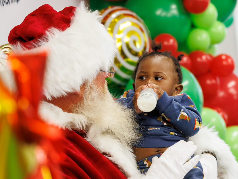 Children's of Mississippi patient Khadedryck Todd of Hattiesburg enjoys a bottle while visiting with Santa Claus during Friends of Children's Hospital's Santa's Workshop event. Melanie Thortis/ UMMC Communications 