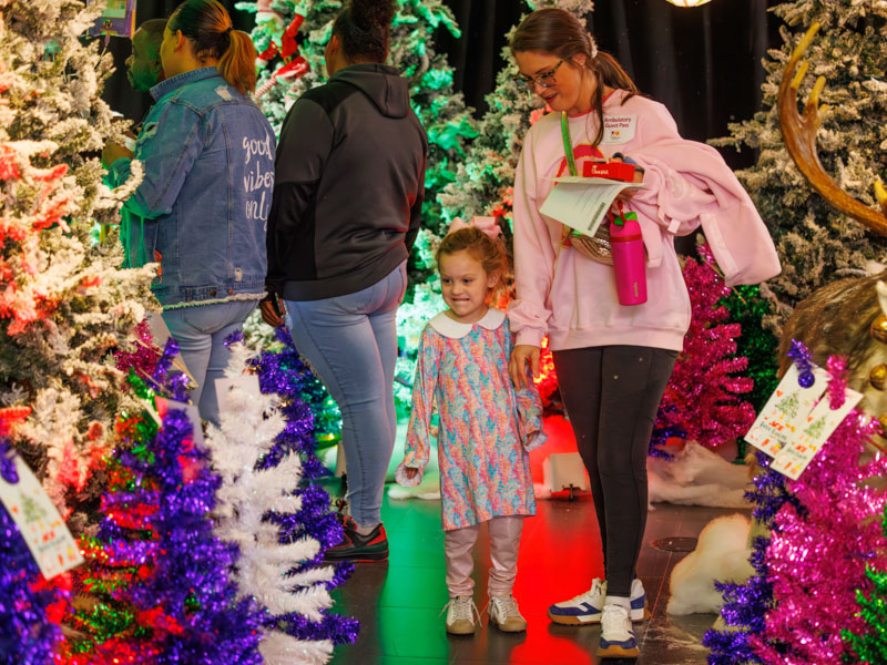 Mae Ellington White and her mom, Lindi White of Madison, looks at the multicolored Christmas trees at BankPlus Presents Winter Wonderland and Ace Tree Farm. Melanie Thortis/ UMMC Communications 